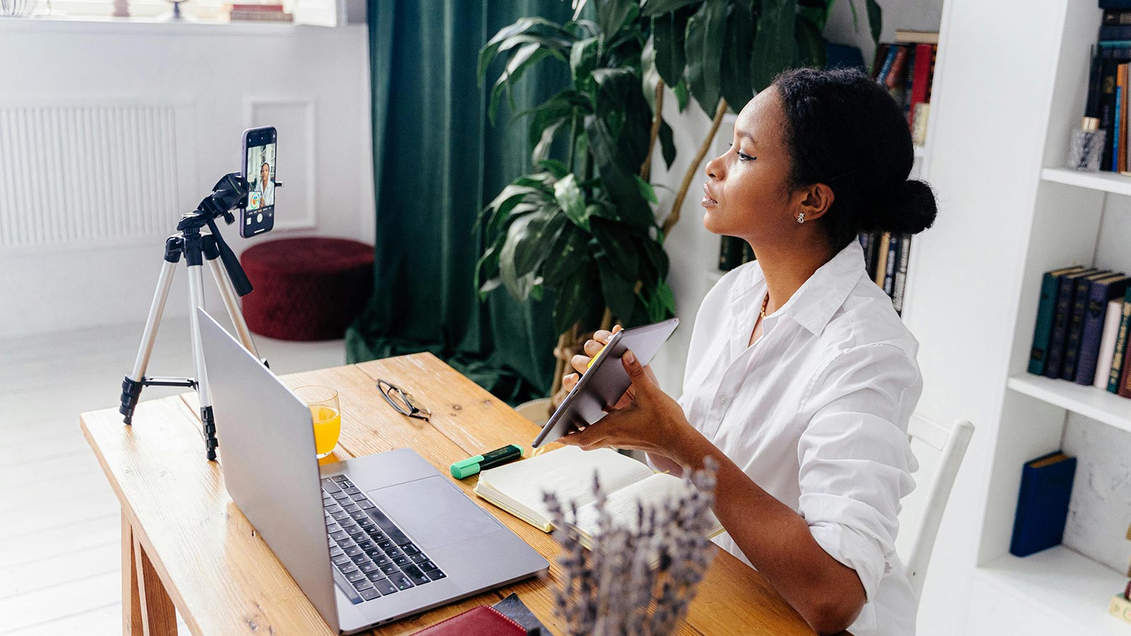 A woman sits at her desk recording a video with a product in her hand, highlighting the growing trust in influencers.