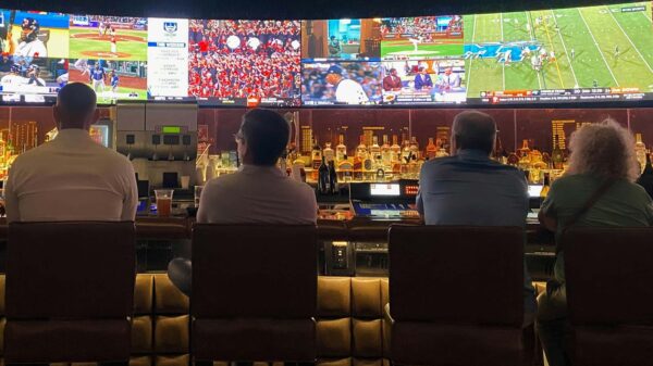 Four people sitting at a bar, watching various types of sports on TV, highlighting the popularity of sports gambling in 2025.