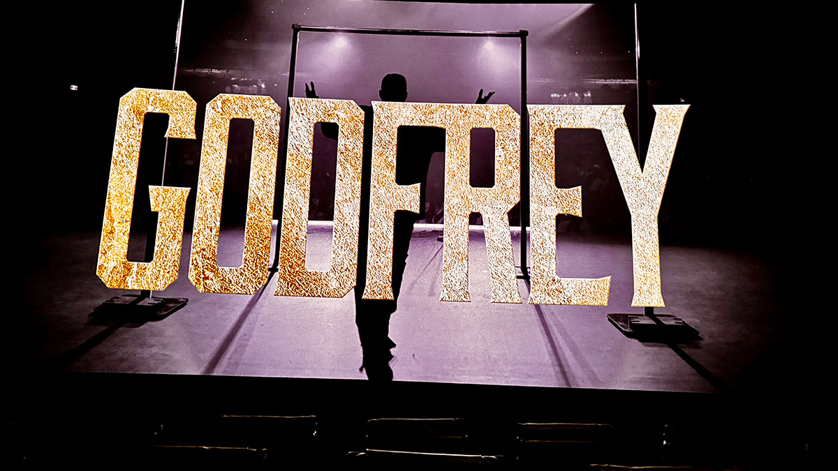 The name Godfrey flashes on the screen at the screening for his new comedy special Rebel with a Cause.