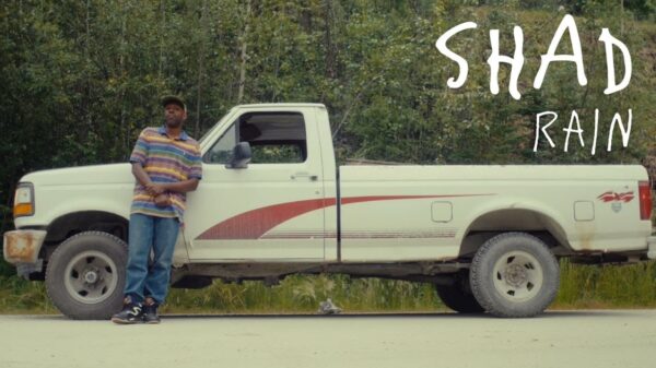 Rapper Shad leans against a car in a scene from his Rain music video.