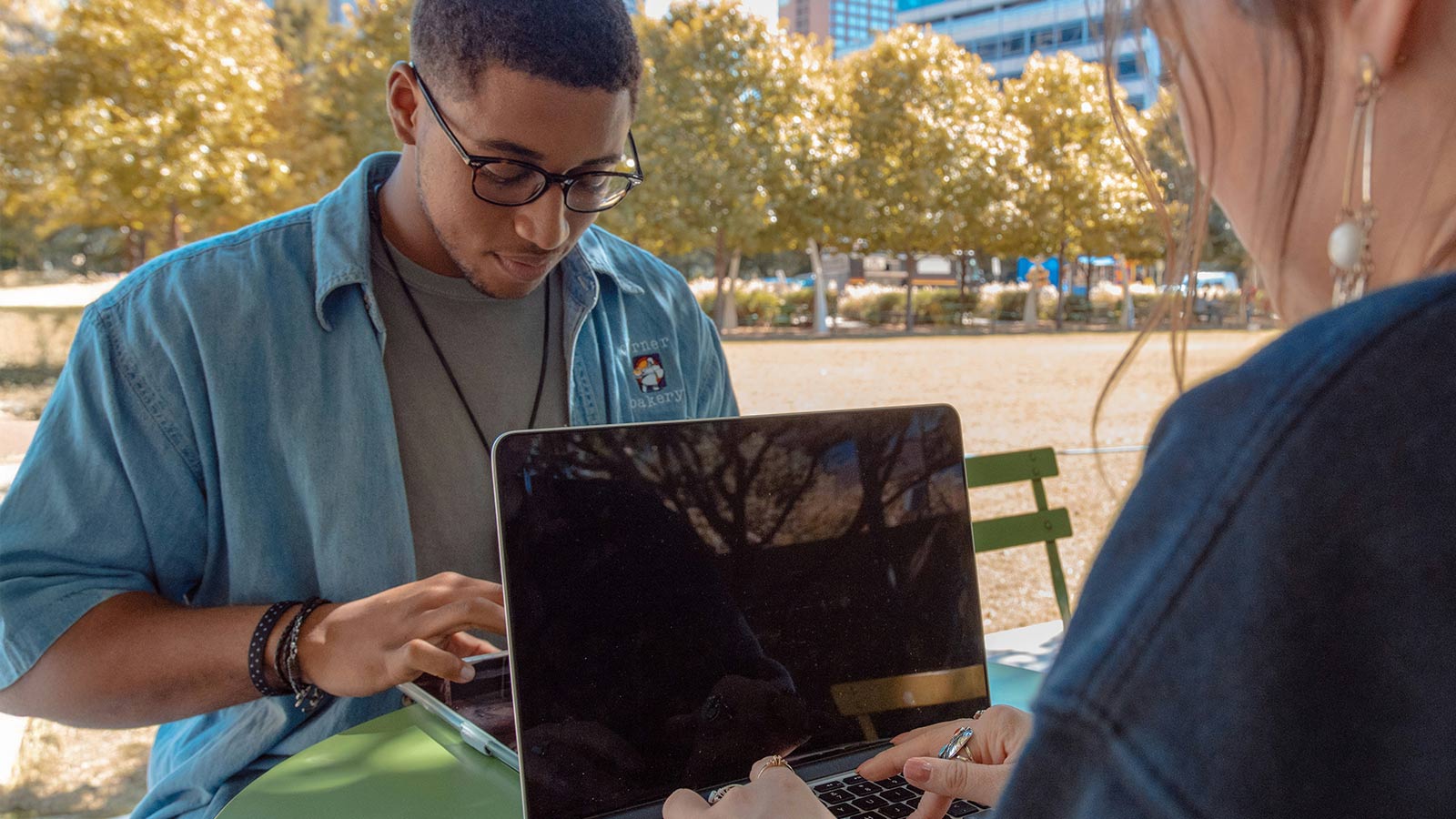 Gen Z students using laptops outdoors as AI reshapes entry-level jobs.