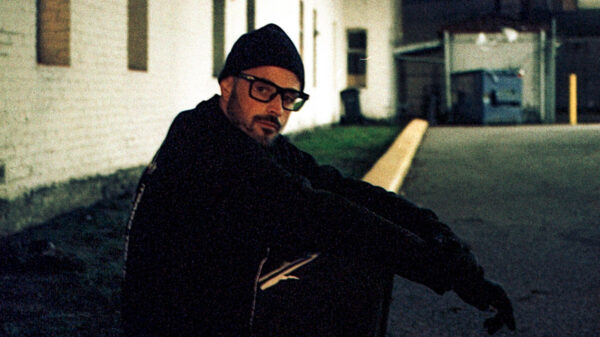 Rapper JUNK sits on a stoop in a promotional image for his new EP, Horrible Pleasures.