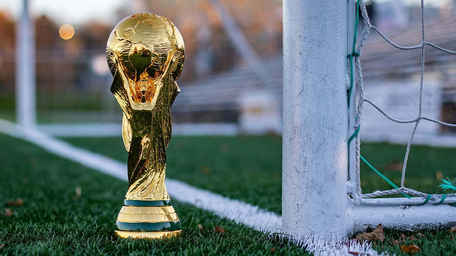 2026 World Cup unity debate illustrated by FIFA World Cup trophy beside a soccer goal on a field.