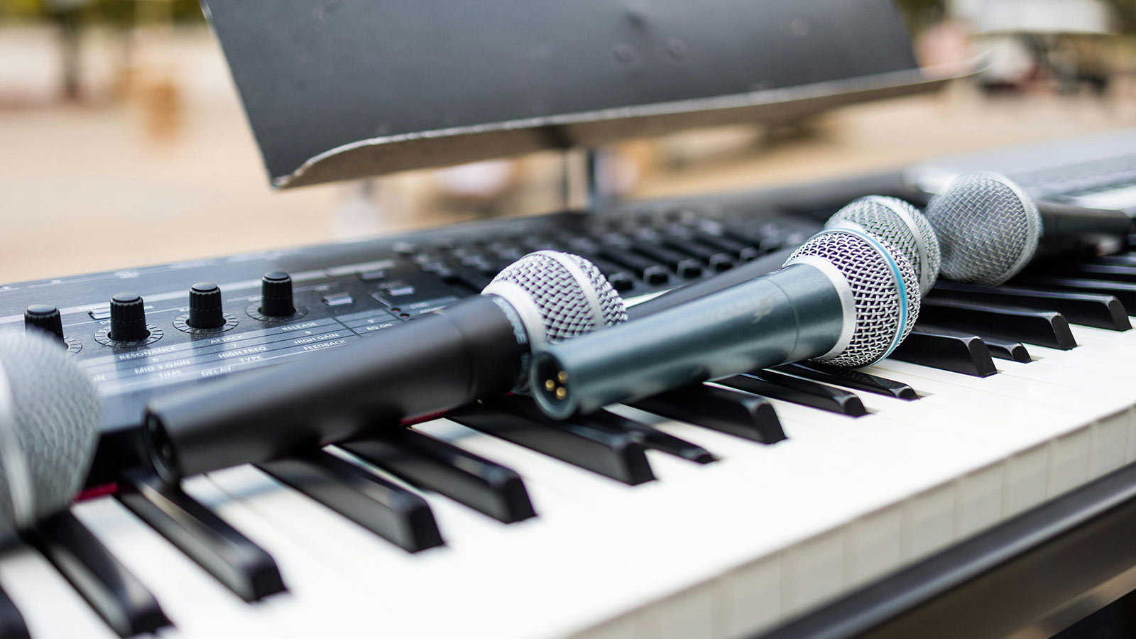 Several microphones resting on an electric keyboard.