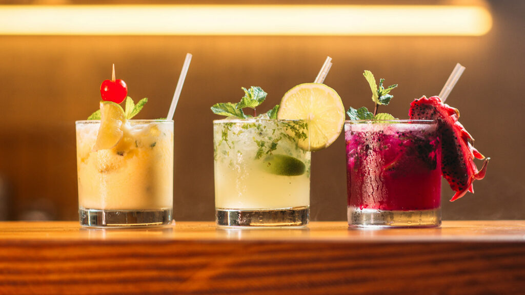 Three mixed drinks on a bar illustrating alcohol use decline in Canada.