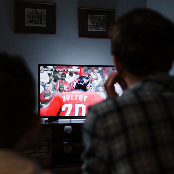 A from behind view of a father and son watching hockey on CBC.