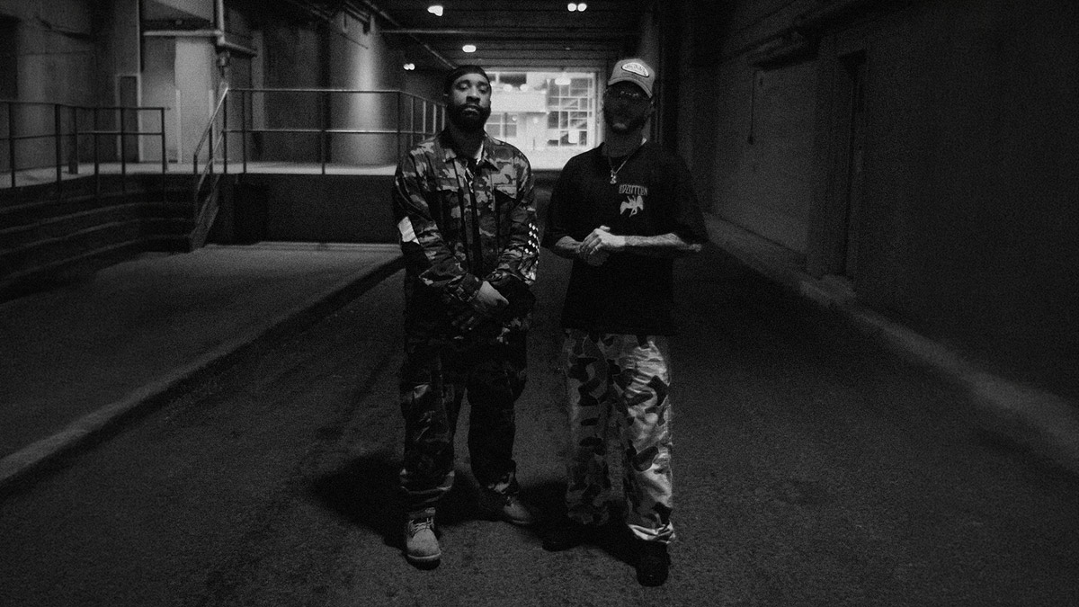 Rappers Tona and Sayzee standing in a parking lot, posing for the camera.