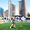 A vibrant soccer scene at Toronto City Hall with players on a sunny day.