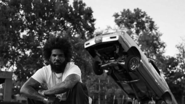 Rapper The Game crouches in front of a hydraulic lowrider on the artwork for his new album The Documentary III.
