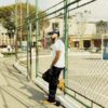 Romeo Don't Die leans against a fence in the Don't Die, I'll Cry music video.