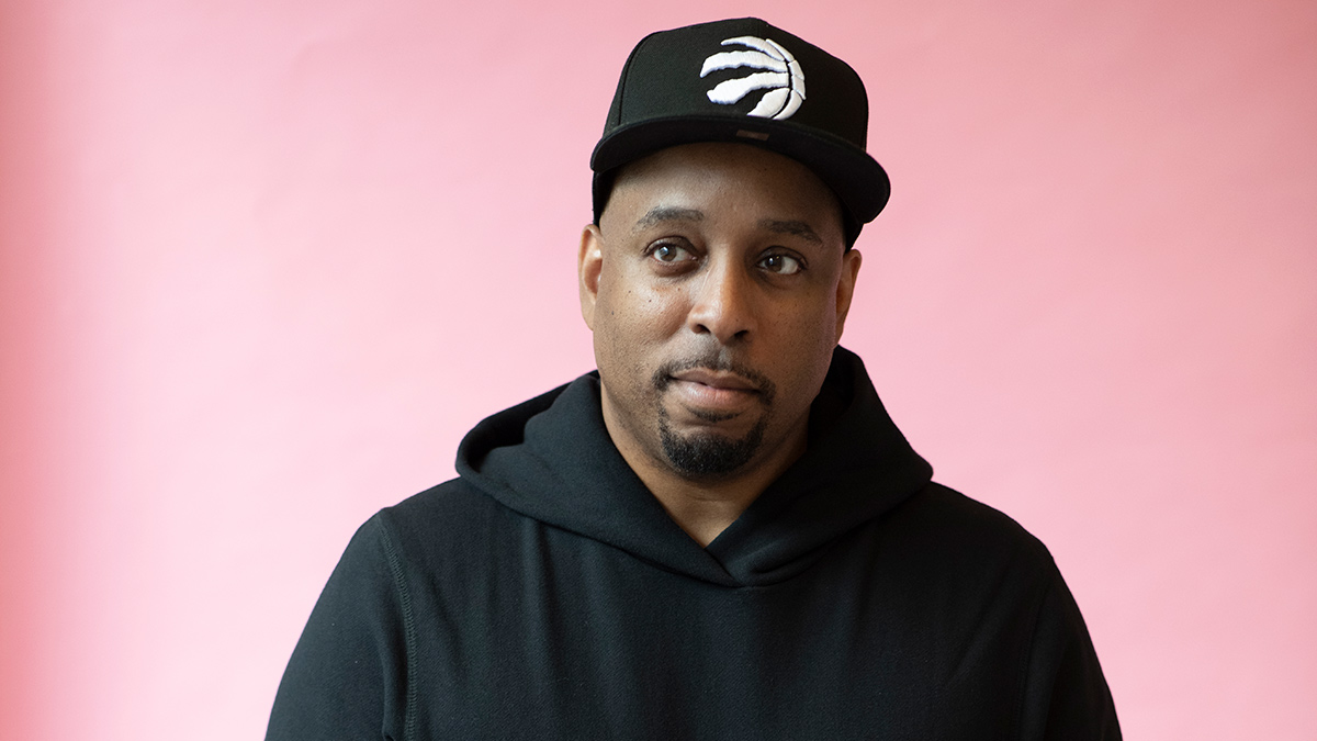 A photo of DJ Agile wearing a black Toronto Raptors hat and a black hoodie.
